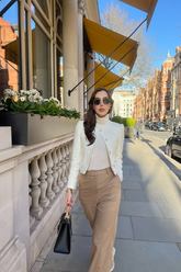 a lady in a white slim sweater, a white jacket and a pair of brown pants